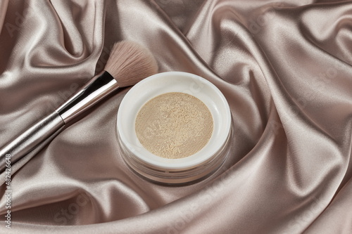 Face powder and brush,on a beige silk pastel background,make up,flat layot