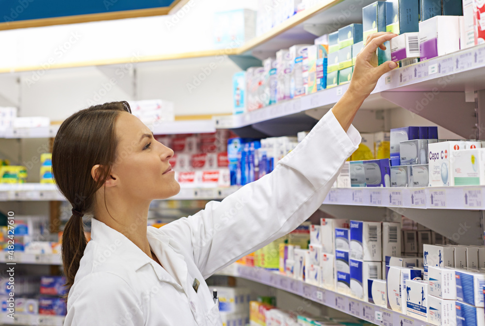 She knows her customer's needs. Shot of an attractive young pharmacist checking stock in an aisle.
