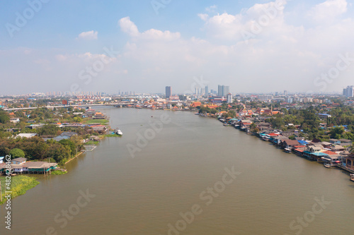 Aerial top view of residential local houses with Phasi Charoen, Chao Phraya canal or river, nature trees, Nonthaburi City, Thailand in urban city town in Asia, buildings. © tampatra