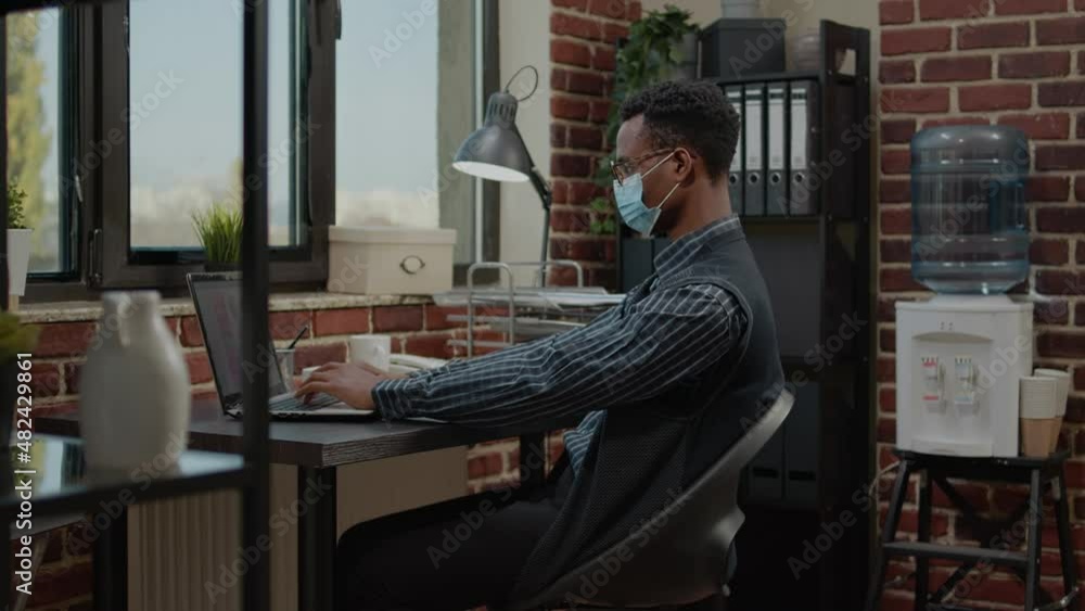 Company employee using laptop to create commercial investment, planning sales statistics for business growth and development. Project manager working on career and wearing face mask. Company employee using laptop to create commercial investment, planning sales statistics for business growth and development. Project manager working on career and wearing face mask.