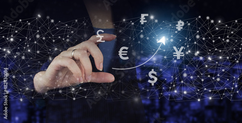 Global currency exchange concept Hand hold digital hologram virtual currency, financial sign on city dark blurred background. Business ideas, currency exchange, and global stock market analysis.