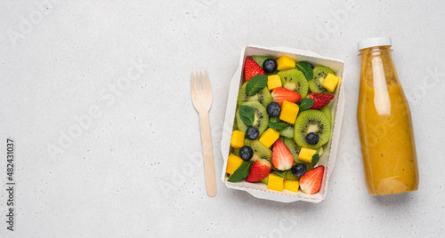 Kiwi, strawberry, blueberry, mango fruit salad in cardboard container. Food delivery to home and office, healthy diet plan concept