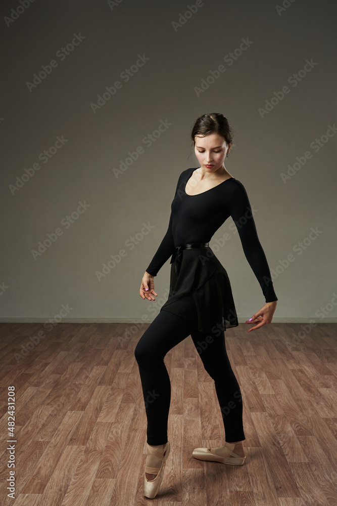 the dancer gracefully stands in pointe shoes on a gray background. dance aesthetics, grace, sensuality the dancer gracefully stands in pointe shoes on a gray background. dance aesthetics, grace, sensuality