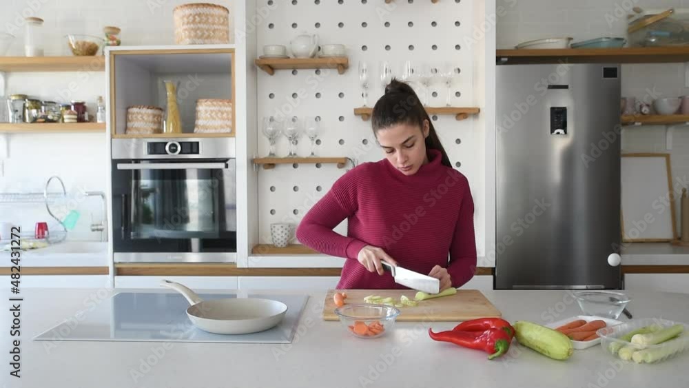 Young vegan woman cooking vegetarian meal in her apartment on modern domestic kitchen cook top. Female preparing food for lunch or dinner, she invited guests at her new home. Young vegan woman cooking vegetarian meal in her apartment on modern domestic kitchen cook top. Female preparing food for lunch or dinner, she invited guests at her new home.