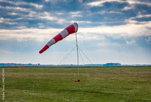 Wind indicator on a dirt airfield against the sky with clouds in summer