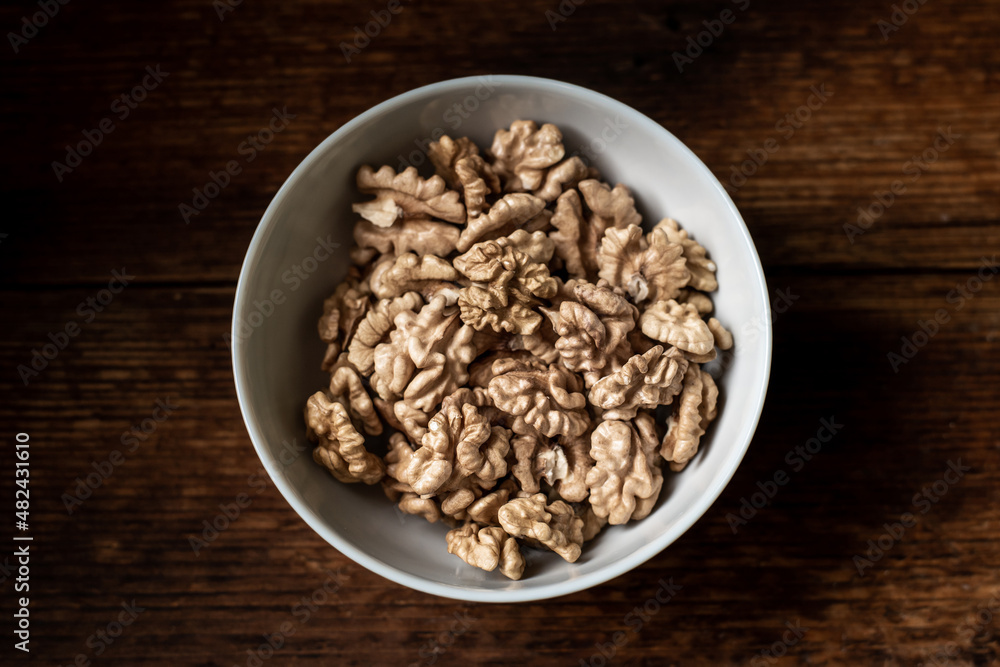 Walnuts in a plate. Dark wooden background. Healthy, wholesome food. Walnuts in a plate. Dark wooden background. Healthy, wholesome food.