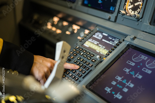 Female pilot inserting flight information into plane system. Airplane control panel. 