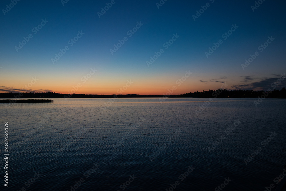 Sunset on a lake with orange gold blue sky. Small ripples in water.