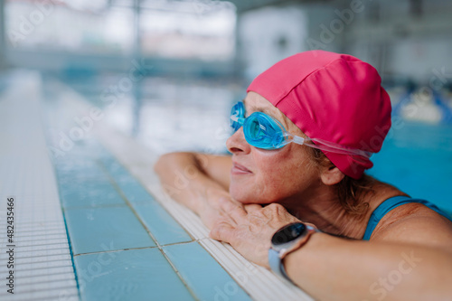 Happy senior woman in swimming pool, leaning on edge. © Halfpoint
