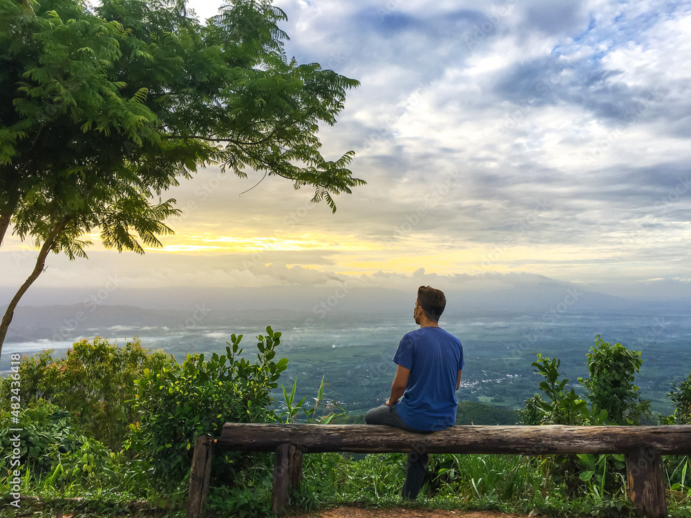 The man relax at mountain with sunshine and color of cloud sky The man relax at mountain with sunshine and color of cloud sky