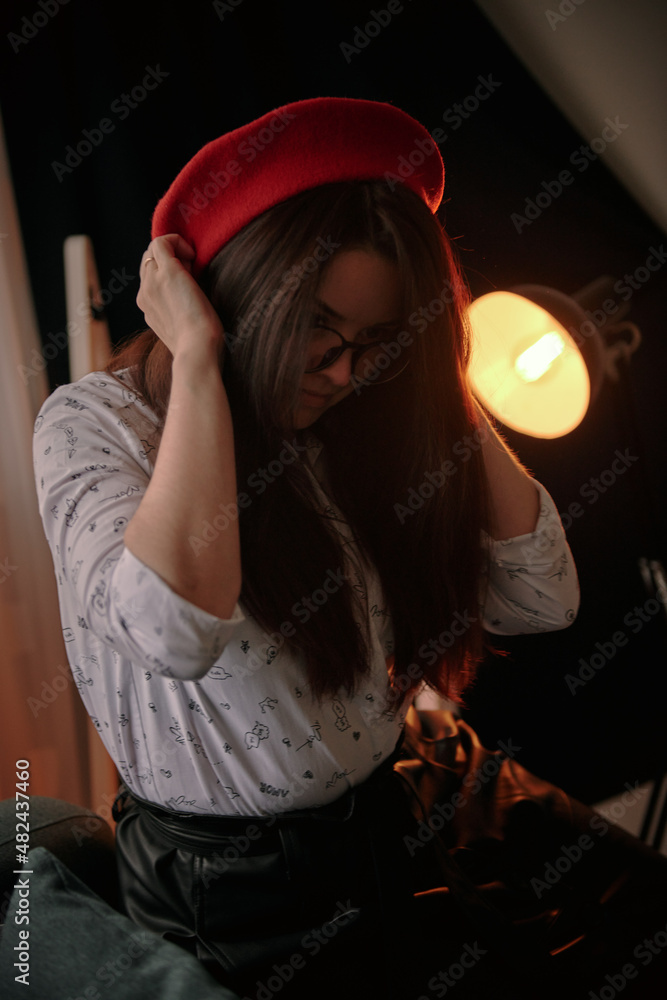 a girl with dark long hair in a red beret and a white blouse, retro style. Indoor soft light a girl with dark long hair in a red beret and a white blouse, retro style. Indoor soft light
