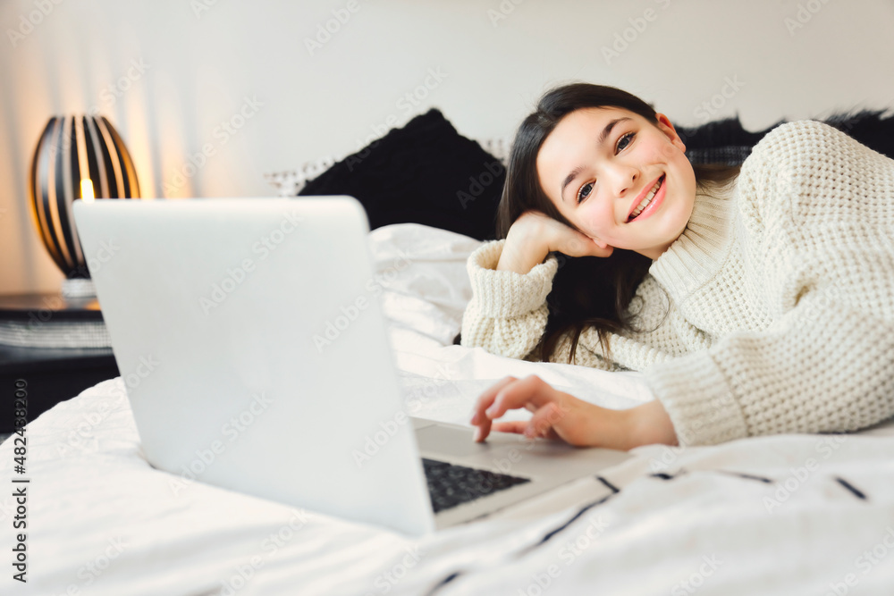 Nice teenage girl using a computer in her bedroom. Nice teenage girl using a computer in her bedroom.