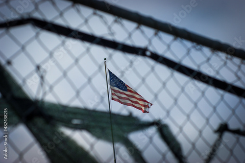 American flag behind old worn fence