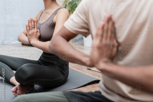 Cropped view of african american couple meditating in living room.