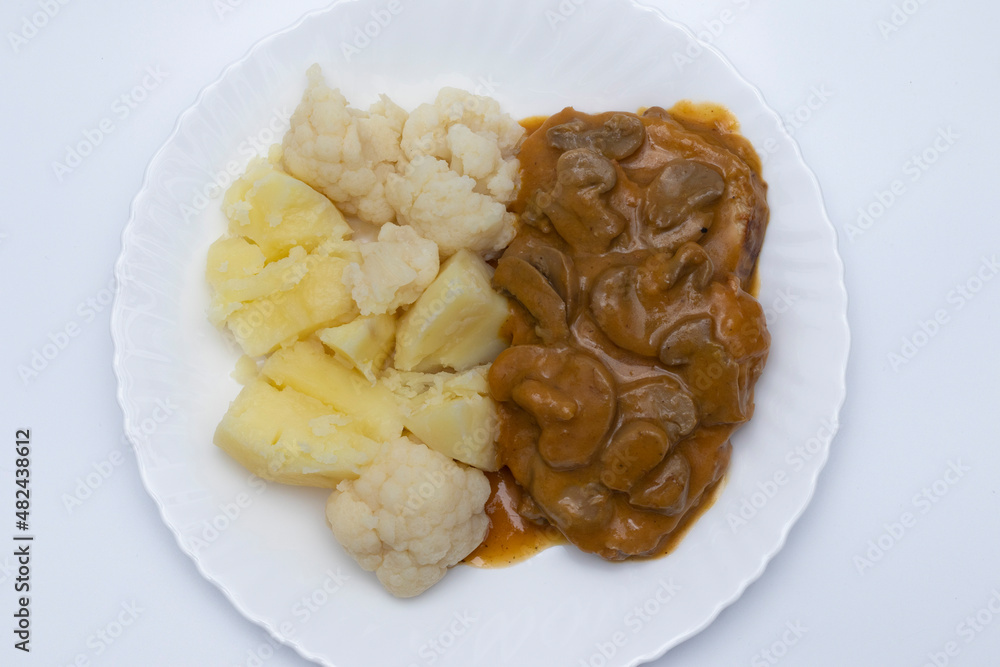 A meat dish with mushroom sauce, accompanied by potatoes with cauliflower. Delicious food concept.