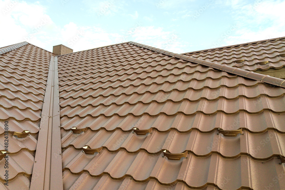 Detail view of house rooftop covered with brown metal tile sheets.