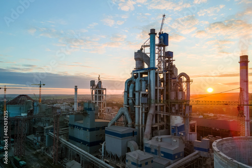 Aerial view of cement factory with high concrete plant structure and tower crane at industrial production area. Manufacture and global industry concept
