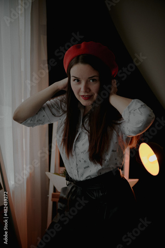 a girl with dark long hair in a red beret and a white blouse, retro style. Indoor soft light