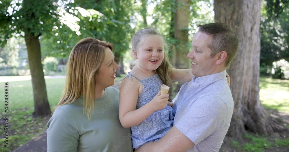 Happy family enjoying time together at park with girl eating ice cream Happy family enjoying time together at park with girl eating ice cream