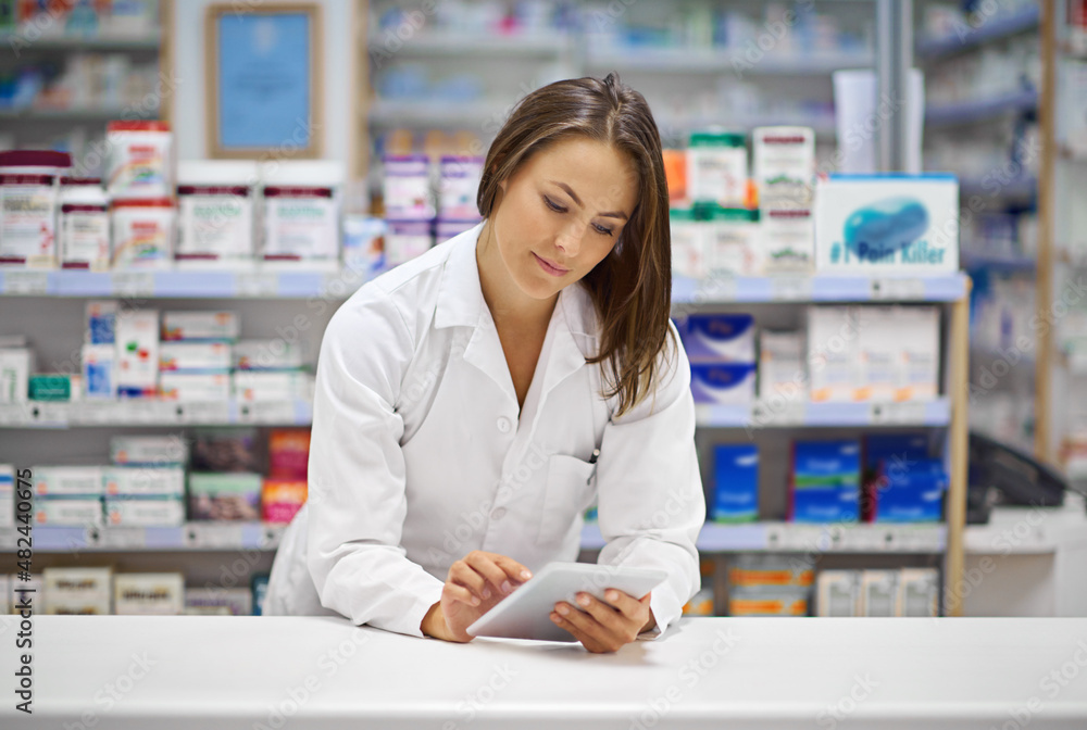 Monitoring prescriptions digitally. Shot of an attractive young pharmacist working at the prescription counter.