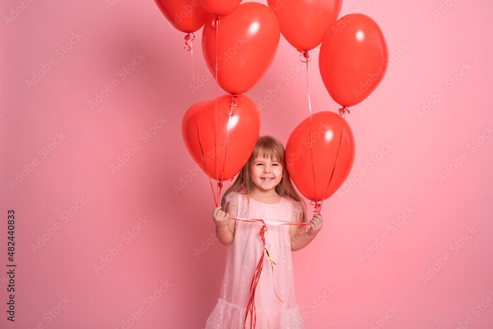 cute child girl in pink dress with red heart balloons on pink background. Valentine day