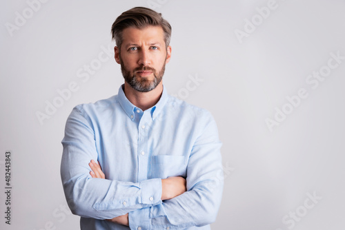 Serious faced man wearing shirt while standing at isolated white background © gzorgz