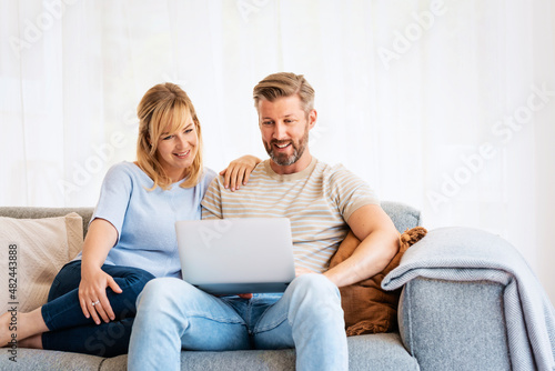 Happy couple using laptop while relaxing on the couch at home