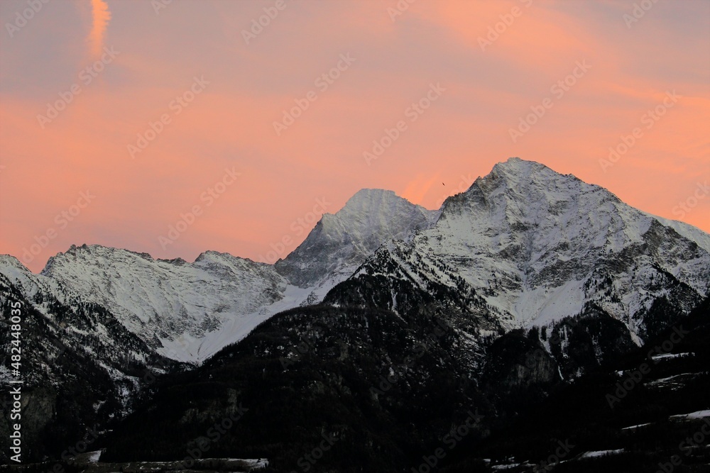 Orange and lilac vivid sunset over snow capped alpine mountains (Aosta, Italy)	