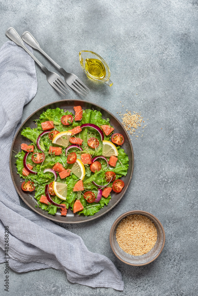 Salad with salmon, fresh vegetables and olive oil. Gray concrete grunge background. Top view, flat lay. Vertical photo. Salad with salmon, fresh vegetables and olive oil. Gray concrete grunge background. Top view, flat lay. Vertical photo.