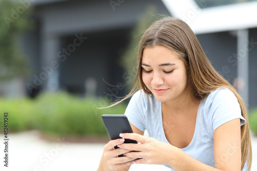 Teenage female checking smart phone in the street
