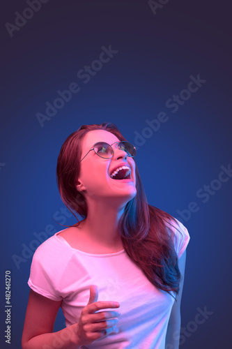 Neon close up portrait of young woman round sunglasses and white dress on dark blue background