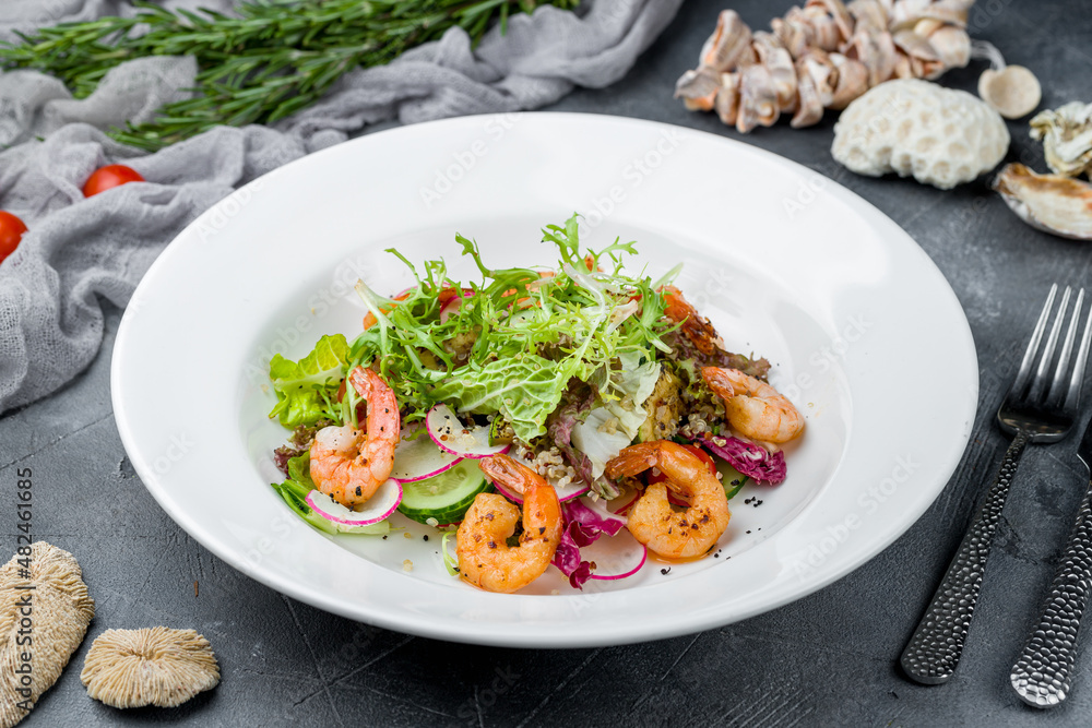 Salad with quinoa and shrimp on white plate on grey table Salad with quinoa and shrimp on white plate on grey table