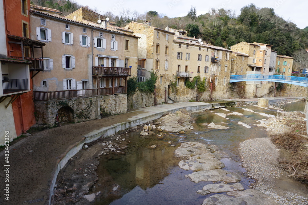 mirror reflection of buildings of the village in the river in the pyrénées, france