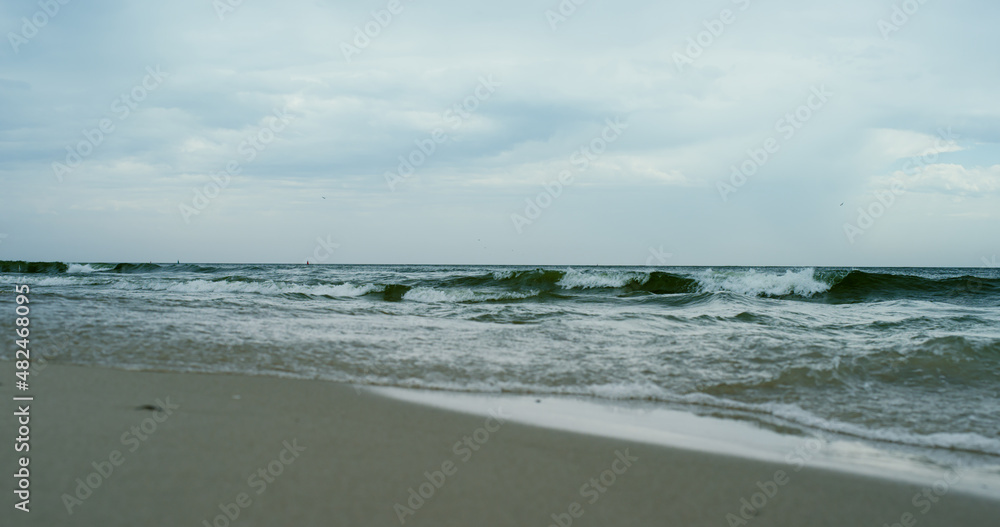 Waves crashing sand beach on grey cloudy weather. Aerial view ocean storming. Waves crashing sand beach on grey cloudy weather. Aerial view ocean storming.