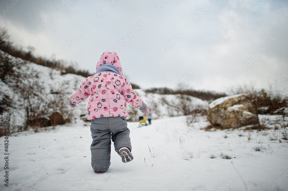 Two baby girl enjoy a sleigh ride. Child sledding. Kid riding a sledge on winter.