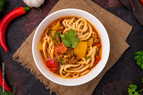 Lagman asian soup with meat, vegetables and noodles, dark table, uzbek cuisine top view photo