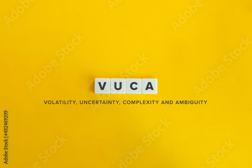 Volatility, Uncertainty, Complexity and Ambiguity (VUCA) banner. Letter tiles on bright orange background. Minimal aesthetics.
