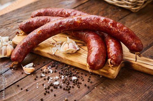 Homemade sausage with garlic cut into slices lies on a wooden table on a cutting board with spices and garlic. Traditional sausage, ready to eat, delicious breakfast. 