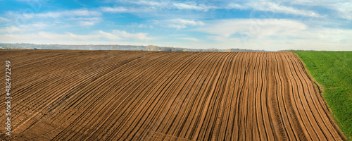 rows of plowed field in spring under a beautiful sky clouds