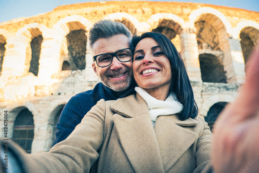 Happy couple of senior tourist having fun taking a selfie in front of famous monument of Italy - Vacation, tourism and travel concept - obrazy, fototapety, plakaty 