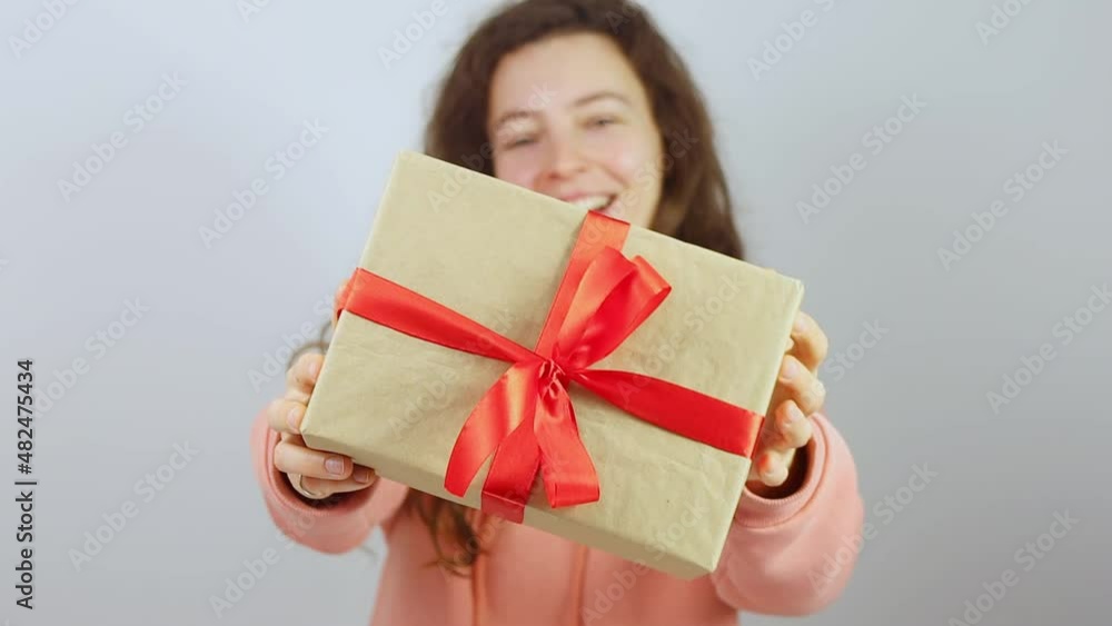 Happy young woman holding and smiling giving giftbox with red ribbon and bow. Congratulating with valentines day, birthday anniversary,declaring love and showing attention.High quality FullHD footage Happy young woman holding and smiling giving giftbox with red ribbon and bow. Congratulating with valentines day, birthday anniversary,declaring love and showing attention.High quality FullHD footage
