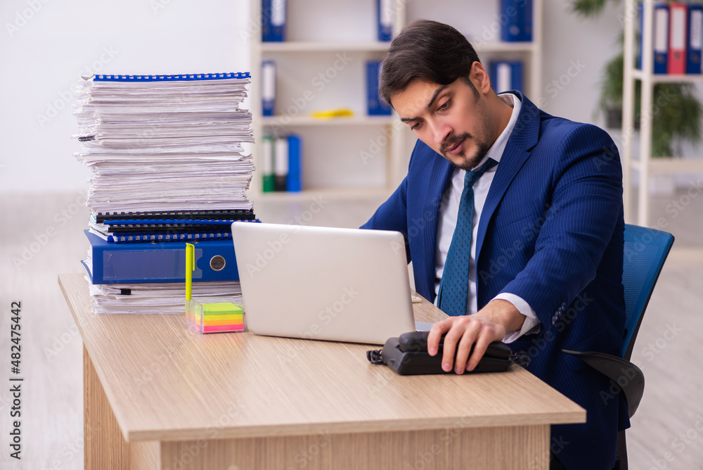 Young male employee and too much work in the office Young male employee and too much work in the office