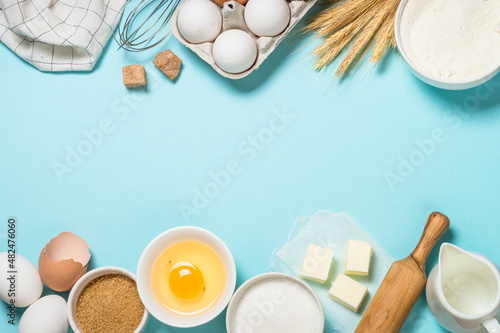 Baking background. Baking ingredients at blue table. Flour, sugar, eggs and utensils. Top view with copy space. photo
