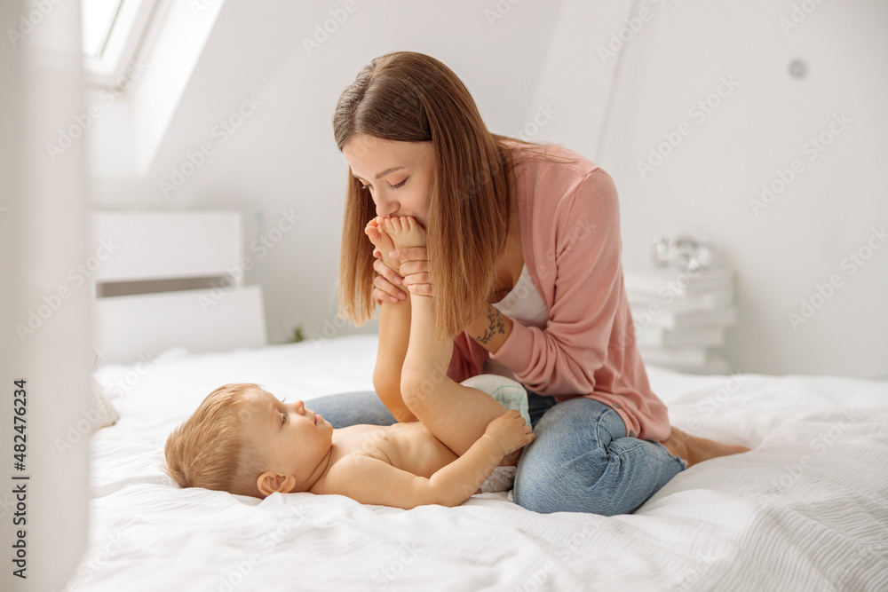 Woman dressing up her little son on the bed Woman dressing up her little son on the bed