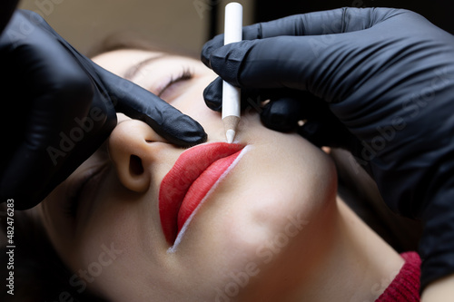 the procedure of permanent lip tattooing the master holds the tip of the lips with his finger and applies the contour with a white pencil