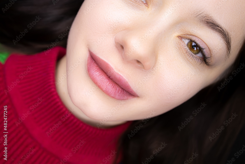 the completed procedure of permanent lip makeup girl model is lying on the couch the completed procedure of permanent lip makeup girl model is lying on the couch