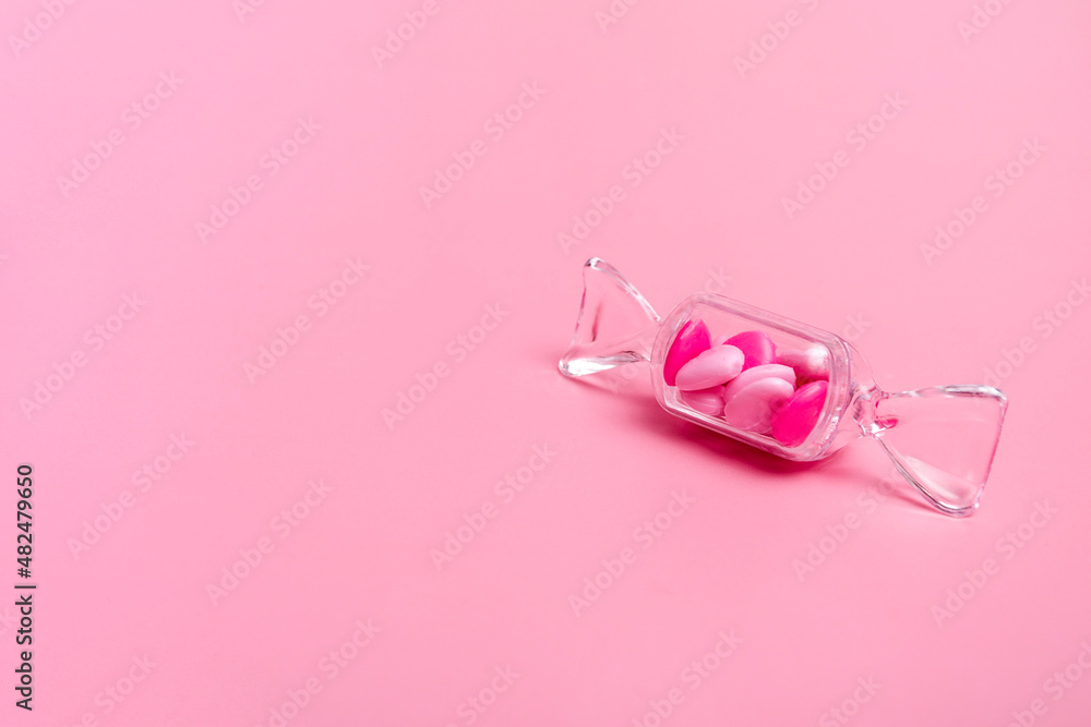 Transparent box in the shape of a candy with sweet heart lollipops on a pink background copy space. Banner
