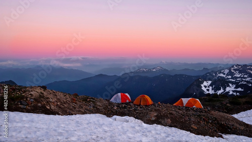 Canvas Print Colorful tents on cliff with scenic expansive  view of mountains at sunset