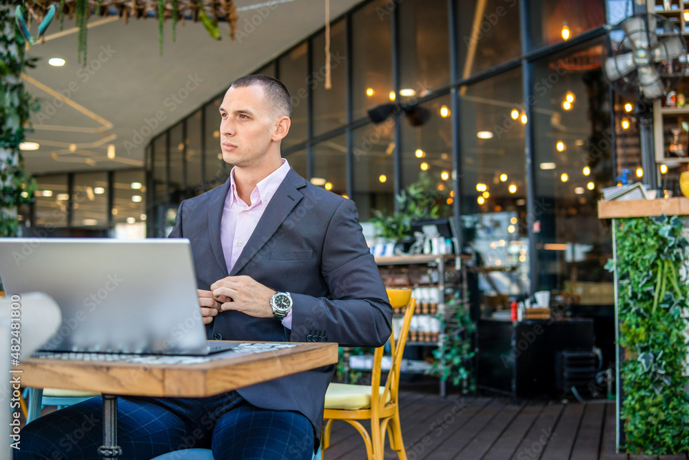 Young handsome businessman working on his laptop while sitting in a cafe Young handsome businessman working on his laptop while sitting in a cafe
