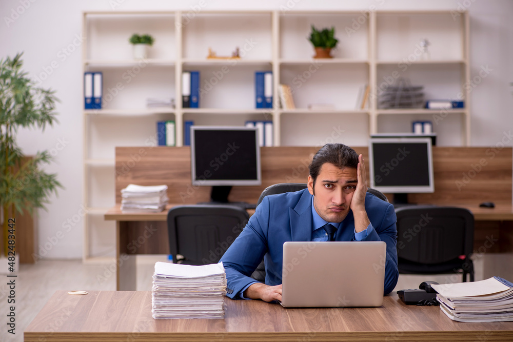 Young male employee and a lot of work in the office Young male employee and a lot of work in the office